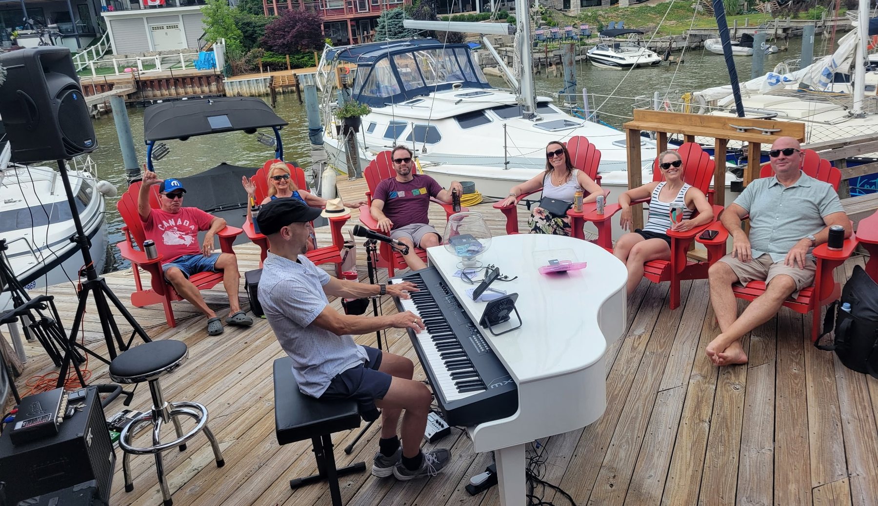An outdoor waterfront deck show with a white grand piano shell and seated guests.
