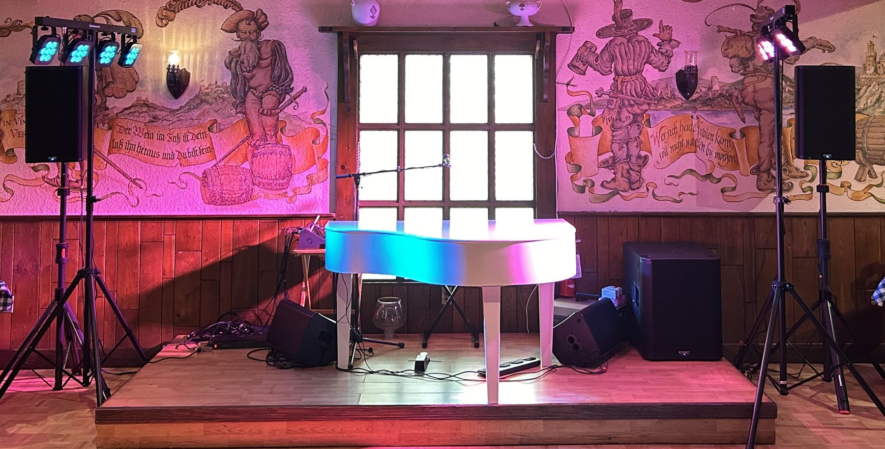 A club stage set with a colour-changing piano shell, monitors and lighting stands.